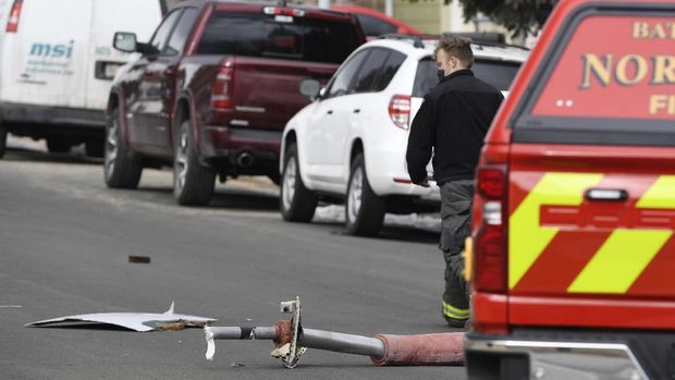 A North Metro firefighter walks past a large piece of an airplane engine in the front yard of a home on Elmwood Street near E. 13th Avenue, Saturday, Feb. 20, 2021, in Broomfield, Colo. Debris from a United Airlines plane fell onto Denver suburbs during an emergency landing Saturday after one of its engines suffered a catastrophic failure and rained pieces of the engine casing on a neighborhood where it narrowly missed a home. (Andy Cross/The Denver Post via AP)