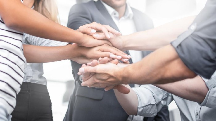 Close up view of young business people putting their hands together. Stack of hands. Unity and teamwork concept.
