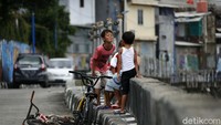 Anak-anak tampak bermain di atas tanggul.