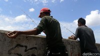 Ada juga warga yang tengah memancing di Sungai Ciliwung.
