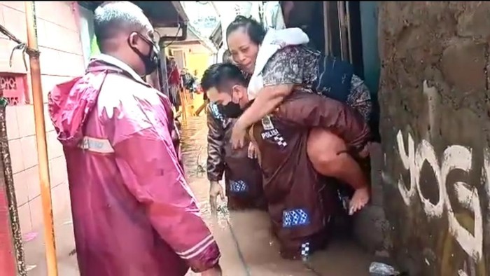 Kapolsek Cilandak Kompol Iskandarsyah menggendong warga yang sakit di lokasi banjir. Screenshot video diberikan Kabid Humas Polda Metro Jaya Kombes Yusri Yunus.