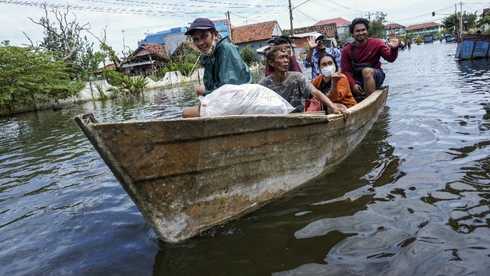OJEK PERAHU SAAT BANJIR Warga pemilik kapal menarik perahu miliknya yang ditumpangi warga melewat banjir di Pekalongan, Jawa Tengah, Minggu (21/2/2021). Untuk mendapatkan penghasilan tambahan, sejumlah warga pemilik perahu memanfaatkan momentum banjir untuk menyewakan perahu miliknya untuk membuka jasa mengantar warga terdampak banjir melewati genangan air dengan biaya antara Rp5.000-Rp15.000 per orang di sepanjang Jalan Kusuma Bangsa dengan jarak sekitar dua kilometer. ANTARA FOTO/Harviyan Perdana Putra/foc.
