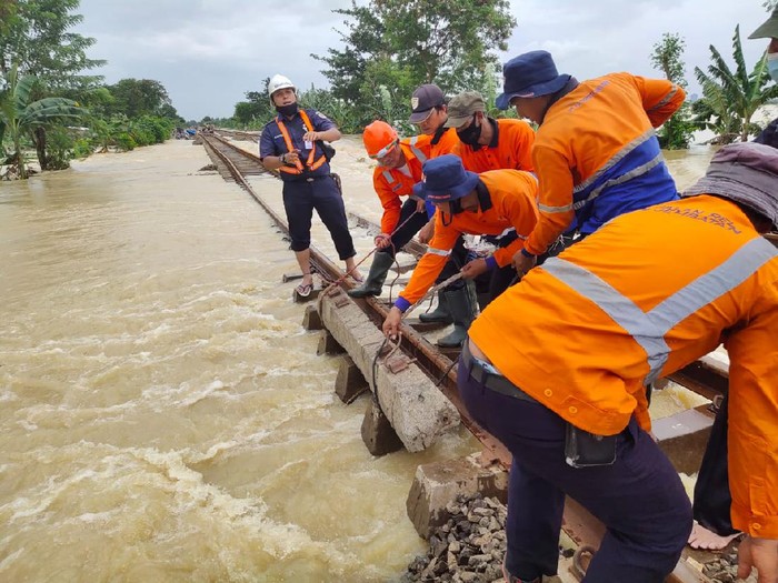 Petugas menangani rel yang menggenangi rel kereta api