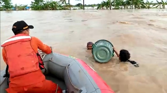 Petugas menyelamatkan dua korban banjir yang menerobos banjir menggunakan ember