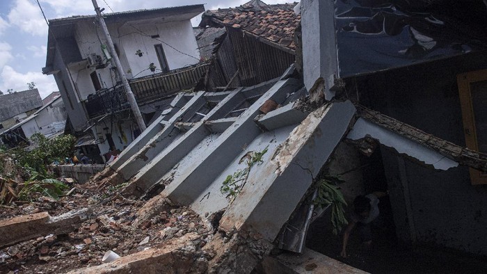 Warga mengambil air di bawah bangunan yang terkena longsor di kawasan Bangka, Jakarta Selatan, Minggu (21/2/2021). Sebanyak lima rumah tertimpa tanah longsor akibat curah hujan yang tinggi pada Sabtu, 20 Februari dini hari namun demikian tidak ada korban jiwa dalam peristiwa itu. ANTARA FOTO/Sigid Kurniawan/wsj.