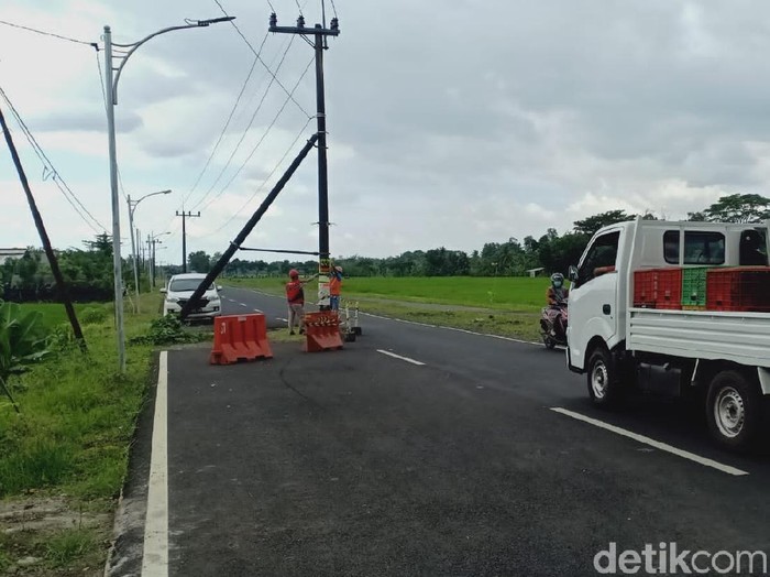 Pemandangan tak lazim tampak di jalan raya Desa Dasri, Kecamatan Tegalsari, Banyuwangi. Ada 7 tiang listrik berdiri di tengah jalan.
