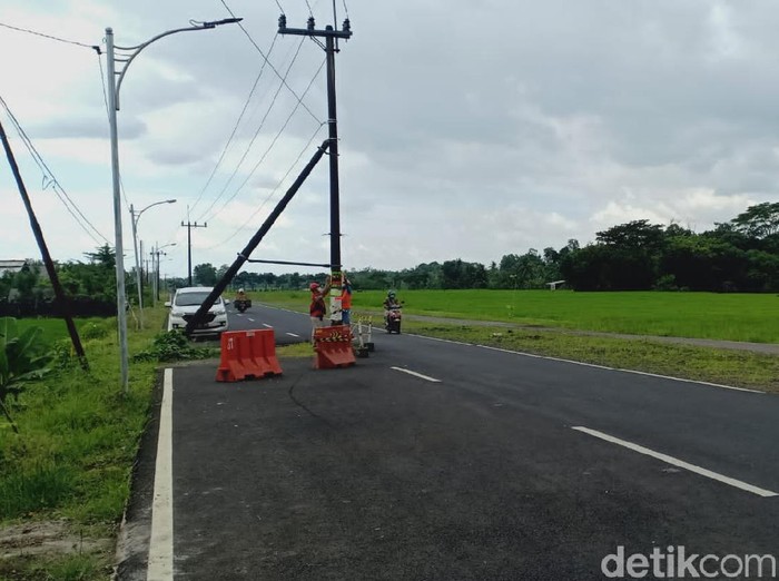 Pemandangan tak lazim tampak di jalan raya Desa Dasri, Kecamatan Tegalsari, Banyuwangi. Ada 7 tiang listrik berdiri di tengah jalan.