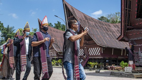 Wisatawan menari tarian tor tor di depan patung Sigale-gale di Desa Wisata Tomok, Simanindo, Samosir, Sumatera Utara, Minggu (21/2/2021). Wisatawan menari tarian tor tor di depan patung Sigale-gale di Desa Wisata Tomok, Simanindo, Samosir, Sumatera Utara, Minggu (21/2/2021).