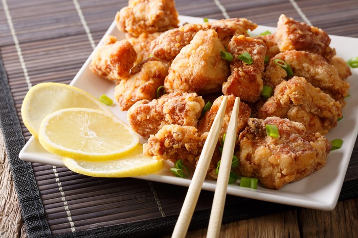 Portion fried chicken karaage with lemon and onion close-up on a plate on the table. horizontal