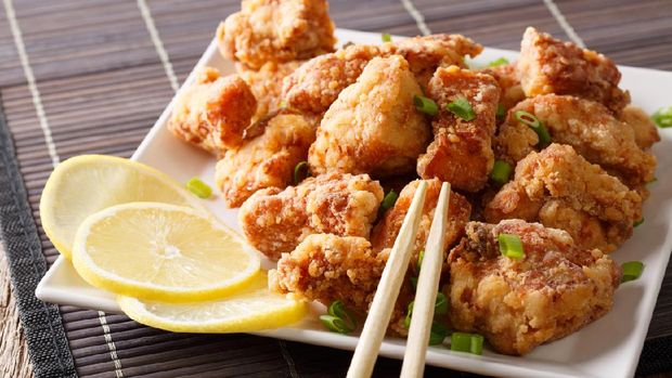 Portion fried chicken karaage with lemon and onion close-up on a plate on the table. horizontal