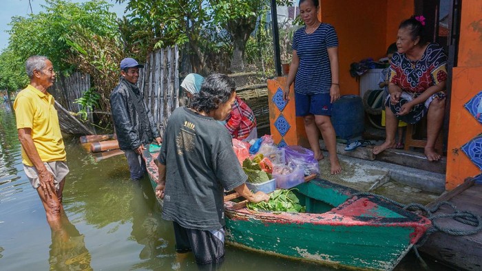 PEDAGANG SAYUR KELILING MENGGUNAKAN PERAHU DAMPAK BANJIR Warga terdampak banjir berbelanja di pedagang sayuran keliling yang menggunakan perahu di Pekalongan, Jawa Tengah, Senin (22/2/2021). Sejak banjir menggenangi Kota Pekalongan, pedagang berinisiatif berjualan menggunakan perahu untuk memudahkan akses melewati banjir. ANTARA FOTO/Harviyan Perdana Putra/rwa.
