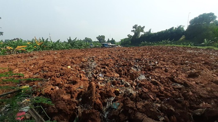 Sampah seluas lapangan sepak bola di Kampung Caman Kota Bekasi, ditutup dengan tanah merah.