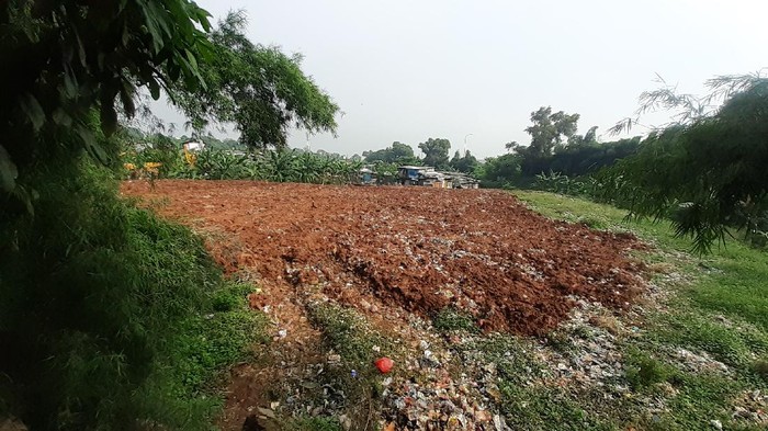 Sampah seluas lapangan sepak bola di Kampung Caman Kota Bekasi, ditutup dengan tanah merah.