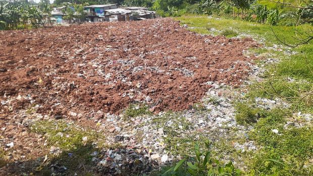 Sampah seluas lapangan sepak bola di Kampung Caman Kota Bekasi, ditutup dengan tanah merah.