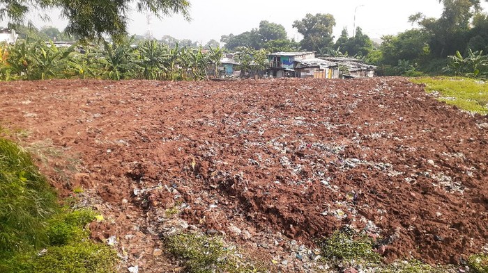 Sampah seluas lapangan sepak bola di Kampung Caman Kota Bekasi, ditutup dengan tanah merah.