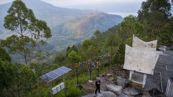 Wisawatan berfoto di kawasan wisata menara pandang Tele dengan latar belakang Danau Toba di Turpuk Limbong, Harian, Kabupaten Samosir, Sumatera Utara, Minggu (21/2/2021). Wisawatan berfoto di kawasan wisata menara pandang Tele dengan latar belakang Danau Toba di Turpuk Limbong, Harian, Kabupaten Samosir, Sumatera Utara, Minggu (21/2/2021).