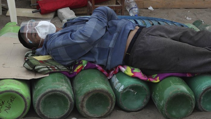 Miris! Warga Peru Rela Antre Berhari-hari Demi Tabung Oksigen A youth rests on his empty oxygen cylinder waiting for a refill shop to open in the San Juan de Lurigancho neighborhood of Lima, Peru, Monday, Feb. 22, 2021, as the lack of medical oxygen to treat COVID-19 patients continues to be the norm nationwide. The shop can only refill about 40 tanks a day, triggering long lines outside private providers with many spending the night outside so as to not lose their place. (AP Photo/Martin Mejia)