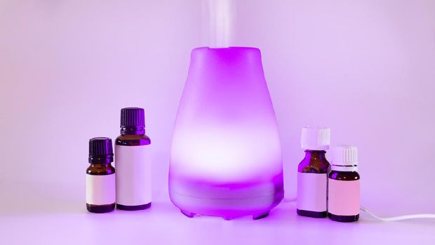 Aromatherapy essential oil diffuser with purple light and oil bottles