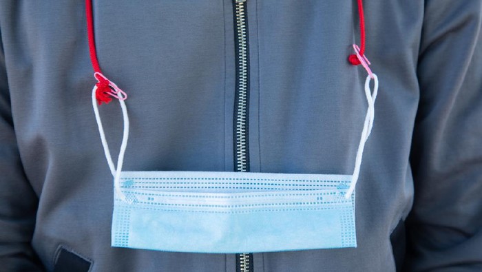 strap masker Close up and front shot of white cotton medical mask hung on the neck with strap on the jacket shows the combination of fashion and safety preparation for health, especially in pandemic of flu virus.