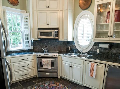 small kitchen in a pool guest house with appliances and cabinets and a counter and custom lighting