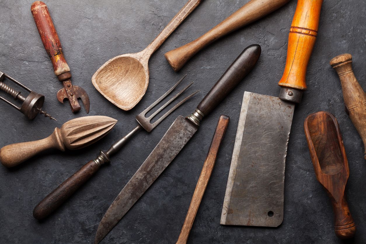 Vintage kitchen utensils, butcher, knife, fork over stone board. Top view
