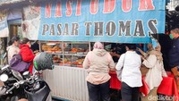Warung itu adalah Nasi Uduk Pasar Thomas yang sejak PPKM berlaku di Jakarta buka lebih awal pada pukul 17.00 WIB. Baru buka saja, nasi uduk ini langsung diserbu pelanggan. Foto: detikFood/Yenny Mustika Sari