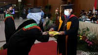 Protokol kesehatan yang diterapkan selama prosesi wisuda berlangsung adalah mengenakan masker hingga menjaga jarak.