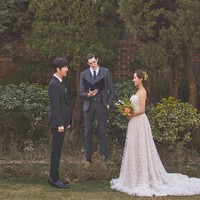 Ini penampakan Oh Yoon Hee (pemain Eugene) dan Ha Yoon Cheol (pemain Yoon Jong Hoon) saat bersanding di hadapan penghulu. Gaun putih yang dukenakan Oh Yoon Hee terlihat simpel dan elegan, dengan rok panjang yang menjuntai. Foto: dok. SBS