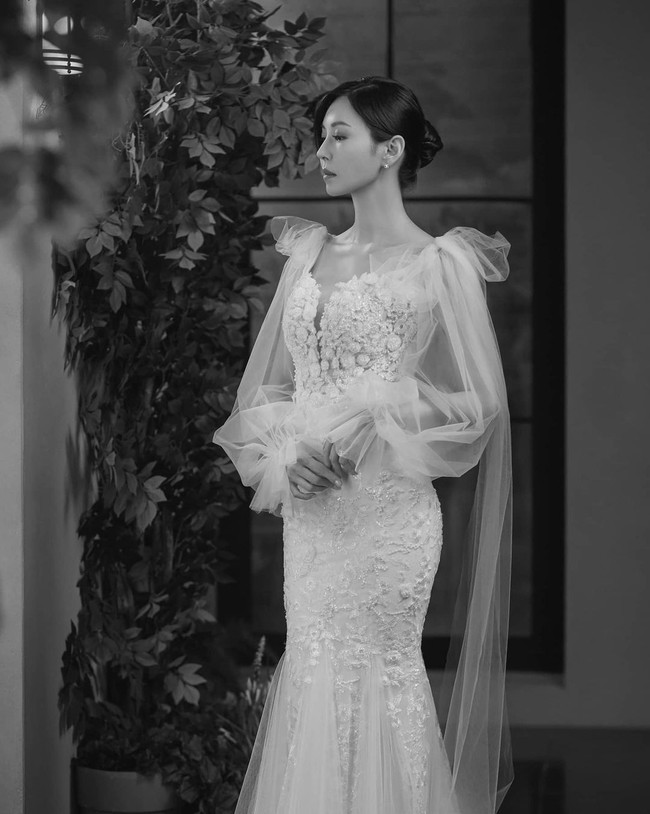 Ini gaun yang dikenakan Cheon Seo Jin (pemain Kim So Yeon) dalam foto pre wedding, bersama suaminya Joo Dan Tae (pemain Uhm Ki Joon). Gaun putih berbahan lace ini semakin mewah dengan aksen cape berbahan tulle di bagian bahu. Foto: dok. SBS