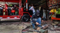Seorang pekerja sedang melakukan pengelasan knalpot. Sementara beberapa pekerja lainnya terlihat sibuk menyelesaikan pembuatan odong-odong yang nyaris rampung.