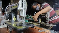 Rusli Lambuk (67 tahun) tengah memperbaiki mesin jahit milik pelanggannya di kiosnya yang berlokasi di kawasan Pondok Labu, Jakarta Selatan, Kamis (25/2/2021).