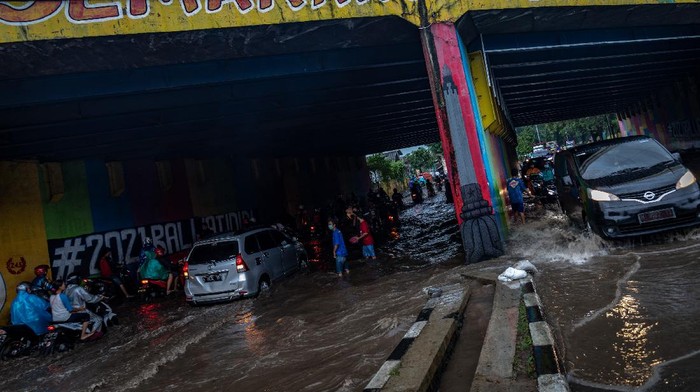 Warga mengarahkan pengendara untuk memanfaatkan trotoar agar sepeda motor mereka tidak mogok saat menembus terowongan dengan tulisan Semarang Hebat!! yang terendam banjir di Jalan Raya Arteri Soekarno-Hatta, Semarang, Jawa Tengah, Kamis (25/2/2021). Banjir yang merendam terowongan jalan raya tersebut dengan ketinggian sekitar 55 cm hingga pukul 18:00 WIB menyebabkan puluhan sepeda motor mogok dan arus lalu lintas terganggu, sementara itu warga setempat membantu mengatur lalu lintas dengan sukarela. ANTARA FOTO/Aji Styawan/foc.