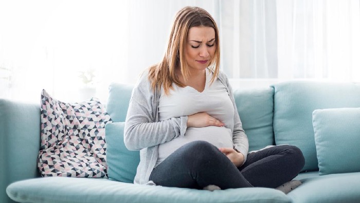 Ibu hamil Young pregnant woman suffering from abdominal pain at home