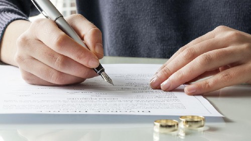 Wife signs divorce decree form with ring