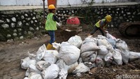 Pekerja memindahkan karung berisi pasir dalam proses penanggulan.