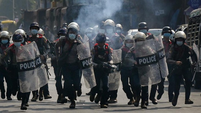 Police run while holding shields as they attempt to disperse protesters taking part in a demonstration against the military coup in Yangon on February 27, 2021. (Photo by Ye Aung THU / AFP)