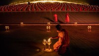 Seorang biksu menyalakan lilin saat menghadiri upacara Magha Pija yang digelar di masa pandemi virus Corona. 