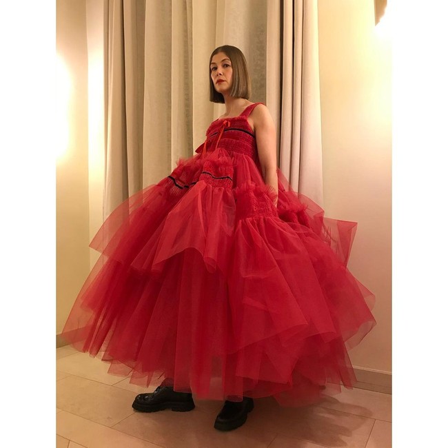 Gaun merah full-tulle nan megar dari desainer Molly Goddard menjadi andalan aktris Rosamund Pike. Uniknya, ia memadukan gaun tersebut dengan boots hitam. (Foto: Instagram)