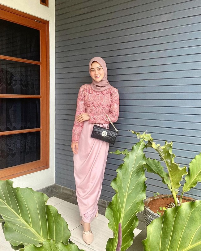 Ketika ke acara pernikahan, Henny tampil dengan dress satin dengan bahan atas lace pastel pink. Dipadu dengan hijab segi empat dengan warna senada.  Foto: Instagram @hennyyrahman.