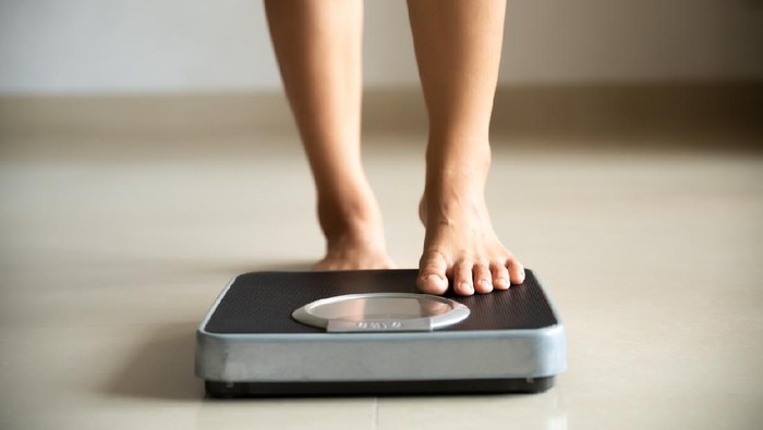 Ilustrasi Diet Female leg stepping on weigh scales. Healthy lifestyle, food and sport concept.