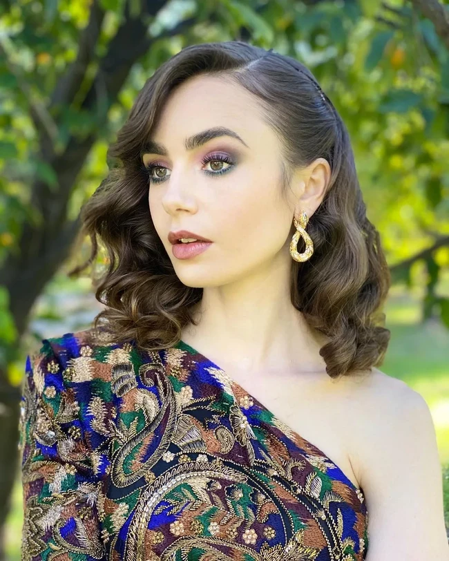 Untuk tampil formal tidak selalu dengan mencepol atau menyanggul rambut. Tampilan rambut Lily Collins ini bisa jadi inspirasi penampilan formal. Rambut bob sebahunya ditata ikal dengan dijepit di bagian samping. Foto: Instagram