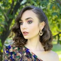 Untuk tampil formal tidak selalu dengan mencepol atau menyanggul rambut. Tampilan rambut Lily Collins ini bisa jadi inspirasi penampilan formal. Rambut bob sebahunya ditata ikal dengan dijepit di bagian samping. Foto: Instagram