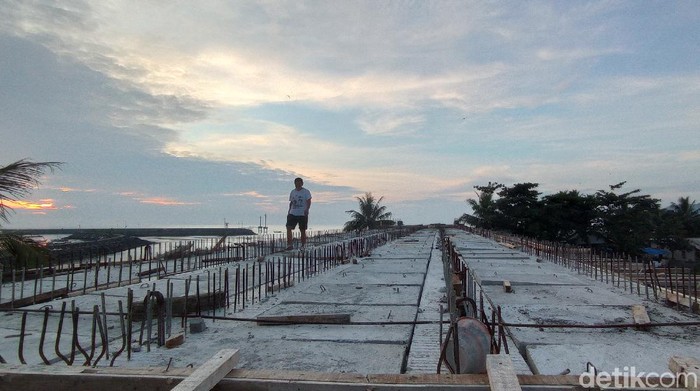 Seorang warga berjalan di atas Jembatan Cikidang Pangandaran yang belum selesai dibangun.