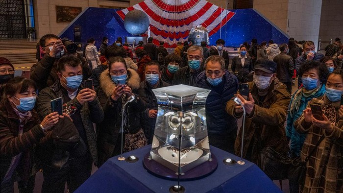 Antusias Warga China Lihat Batuan yang Diambil dari Bulan BEIJING, CHINA - MARCH 02: Visitors stand in front of equipment from China's space program that is part of a display at the National Museum of China on March 2, 2021 in Beijing, China. China's mission to the Moon marked the first time in 40 years that fresh lunar rock samples were returned to Earth. The unmanned spacecraft, called Chang-e 5, collected roughly 4 pounds of rock and debris from a region of the Moon's surface that had not been previously explored. China has been pouring billions of dollars into its ambitious space program that aims to land astronauts on the Moon by 2030. Scientists in the U.S. say the new lunar material could help to better understand the Moon's evolution. (Photo by Kevin Frayer/Getty Images)