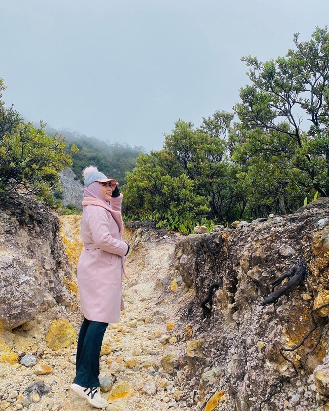 Pada umumnya seseorang yang ingin naik gunung mempersiapkan busana tebal yang bisa menghangatkan badan. April Jasmine pun memilih untuk memakai long coat pink dengan atasan dan bawahan hitam. Ia juga memadukan dengan New York Yankees Sneakers. Foto: Dok. Instagram @apriljasmine85.