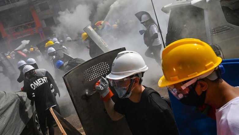 Demonstran antikudeta di Myanmar memakai helm pelindung dan membawa tameng saat bentrok dengan polisi Protesters holding homemade shields as they run during a demonstration against the military coup in Yangon on March 3, 2021. (Photo by STR / AFP)