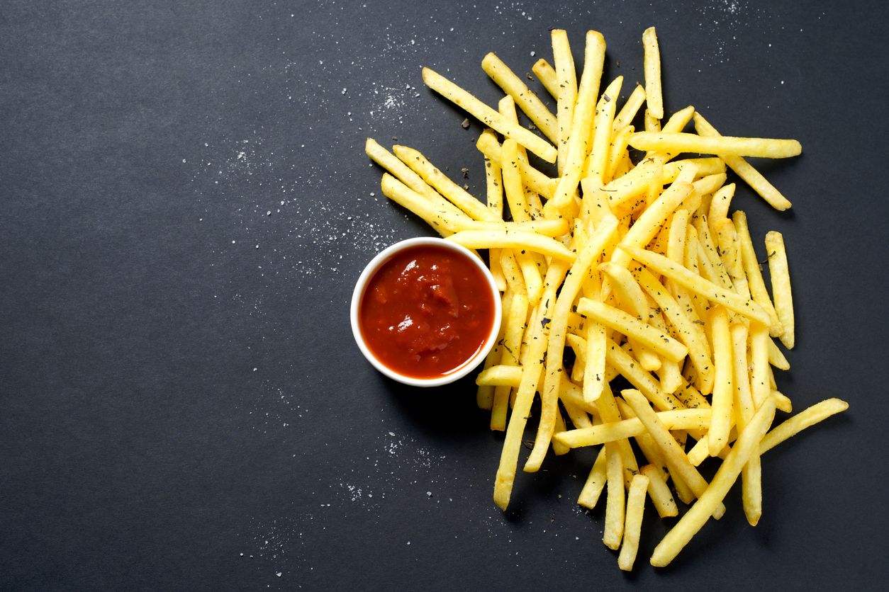 French fries with tomato sauce on a black background.