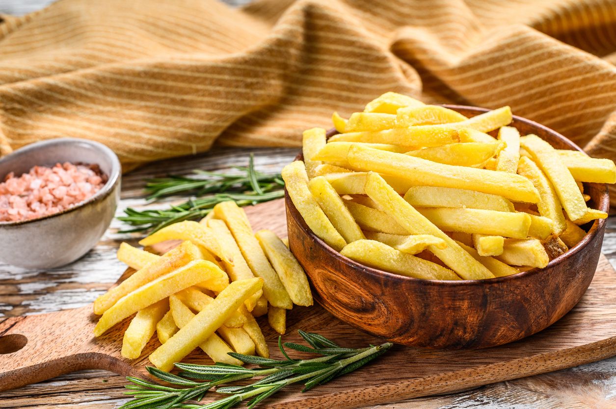 Frozen potatoes in a bowl, French fries, canned food. White background. Top view.