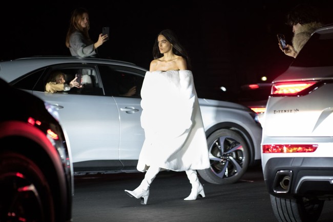 Sementara para model berjalan di antara mobil-mobil yang terparkir. Para supir pun menyalakan lampu dim sebagai penerang ruangan kala model melenggang di runway. Foto: Getty Images/Pascal Le Segretain