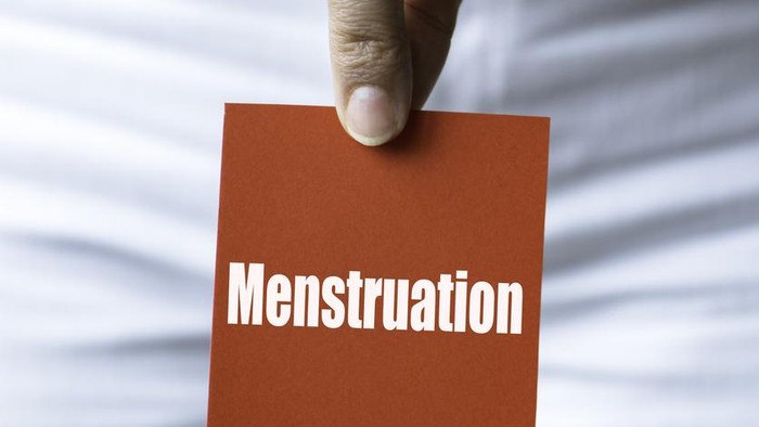 Ilustrasi menstruasi Torso of an unrecognizable woman is showing red square card to camera representing with menstruation written in white.